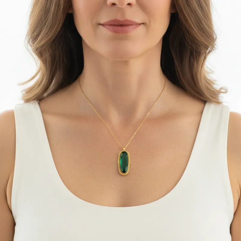 Woman wearing an emerald column pendant necklace on gold, May birthstone jewelry