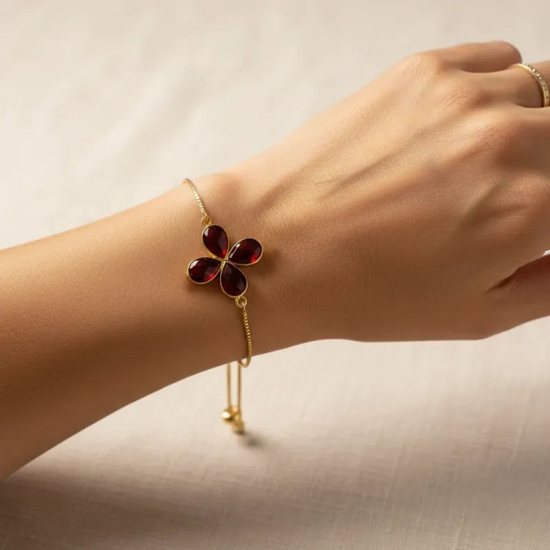 Woman wearing a garnet clover charm bracelet, January birthstone jewelry