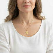 Woman wearing a rhombus sun, moon and star necklace in gold, celestial jewelry