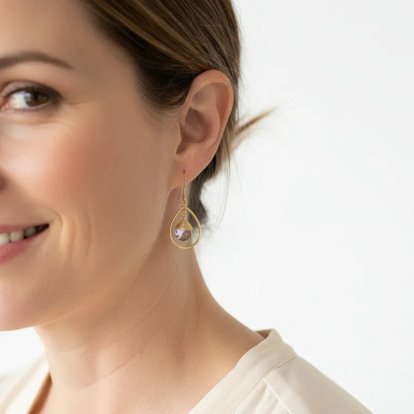 Woman wearing gold fine hoop earrings with amethyst drops