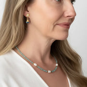 Woman wearing blue topaz orchid stud drop earrings with an aquamarine and potato pearl necklace — one-of-a-kind gold jewelry