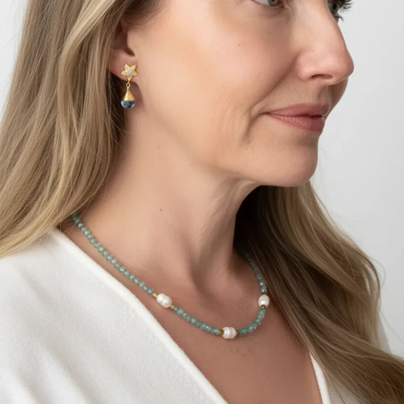 Woman wearing blue topaz orchid stud drop earrings with an aquamarine and potato pearl necklace — one-of-a-kind gold jewelry