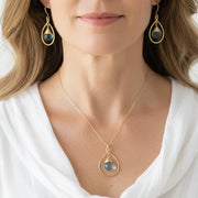 Woman wearing blue topaz earrings with a matching necklace, December birthstone jewelry