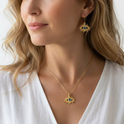 Woman wearing a blue topaz third eye necklace and earring set in gold, December birthstone jewelry