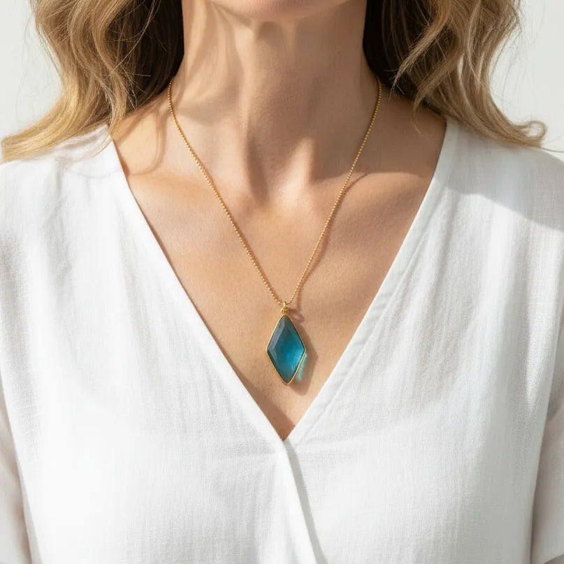Woman wearing a capri blue spike drop necklace in gold, ocean element jewelry