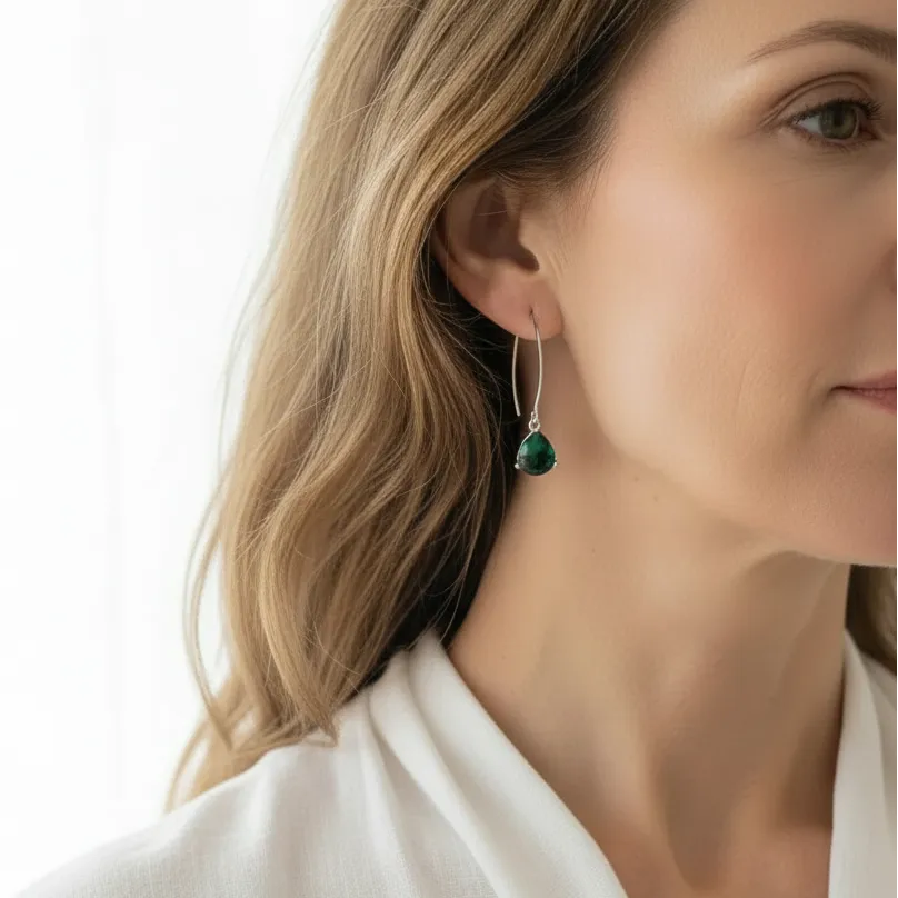 Woman wearing emerald green Cleo triangle drop earrings, May birthstone jewelry