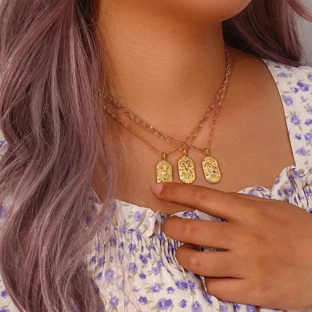 Close-up of a person wearing gold necklaces with pendant charms.