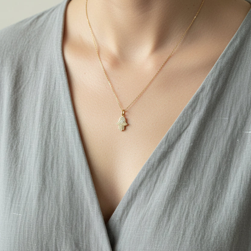 Crystal hamsa hand necklace worn with a soft grey wrap top