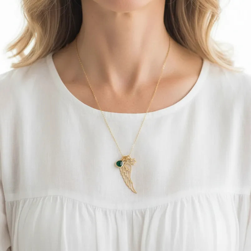 Woman wearing an emerald green angel wing pendant necklace, May birthstone jewelry