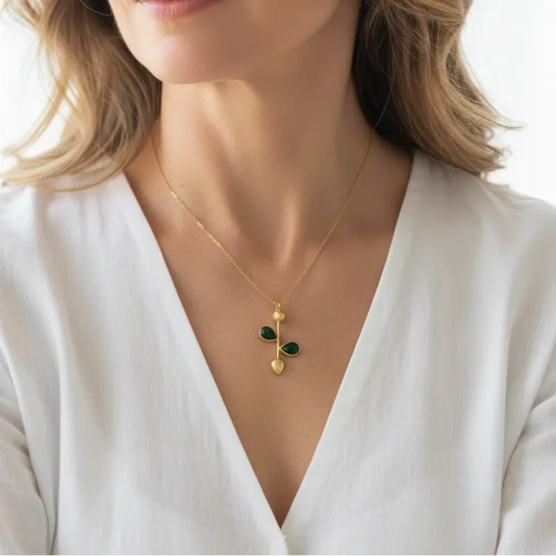Woman wearing a gold plated emerald leaf necklace, May birthstone jewelry