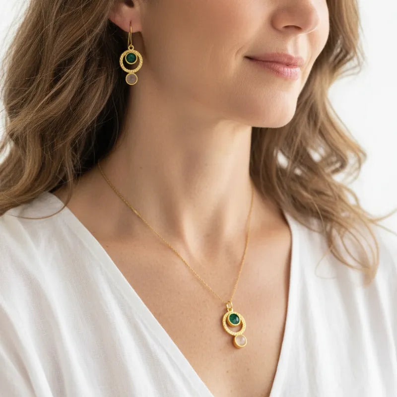 Woman wearing an emerald and moonstone necklace with matching earrings, May birthstone jewelry