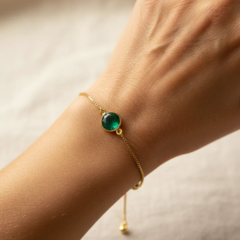 Woman wearing an emerald green round bead bracelet in gold