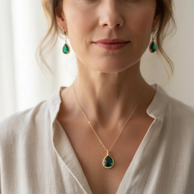 Woman wearing emerald green teardrop necklace and earrings, May birthstone jewelry