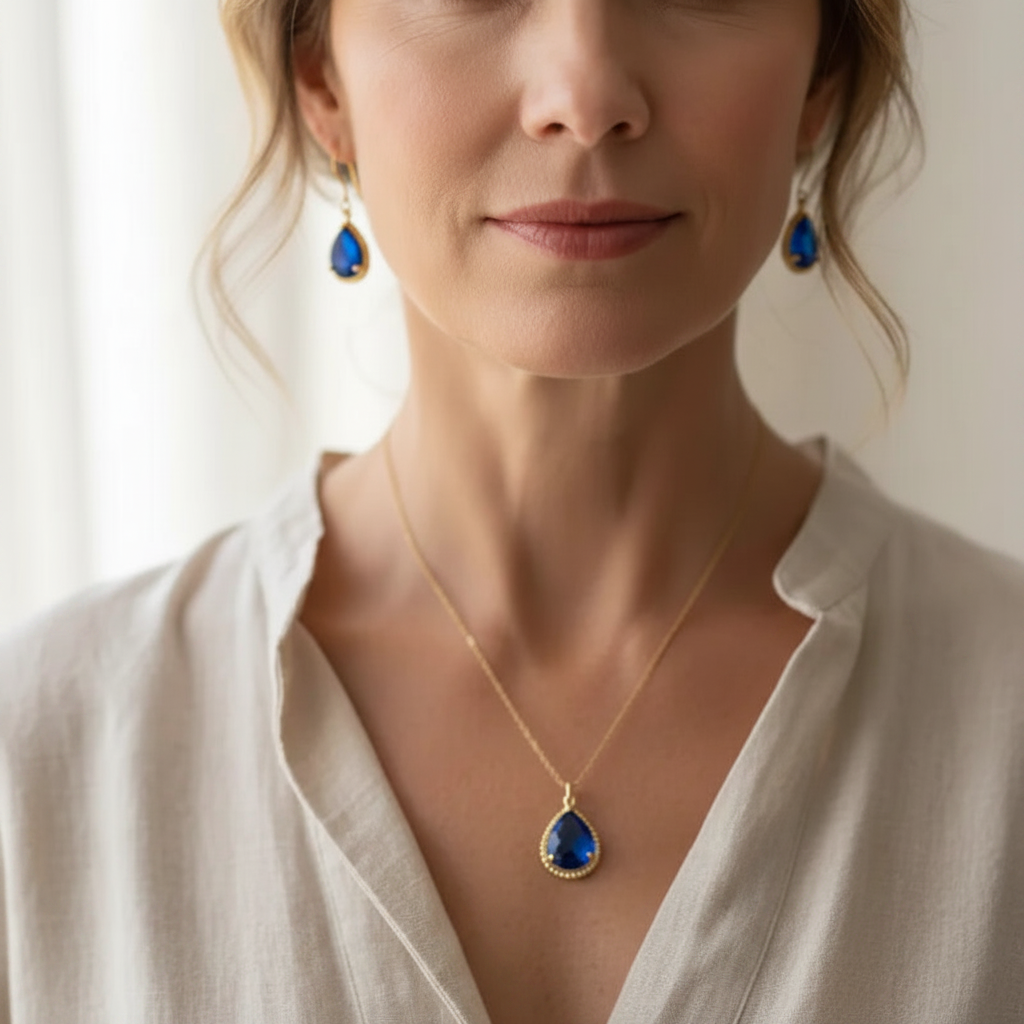 Woman wearing sapphire blue exquisite necklace and earrings in gold, September birthstone jewelry