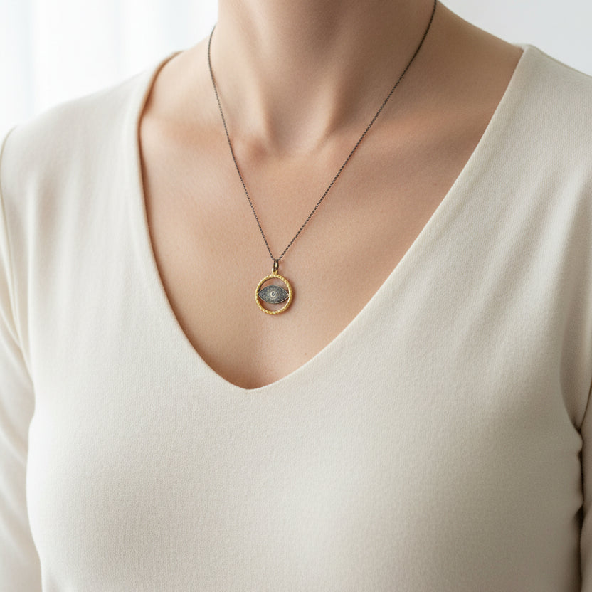 Woman wearing a gold and gunmetal evil eye pendant necklace