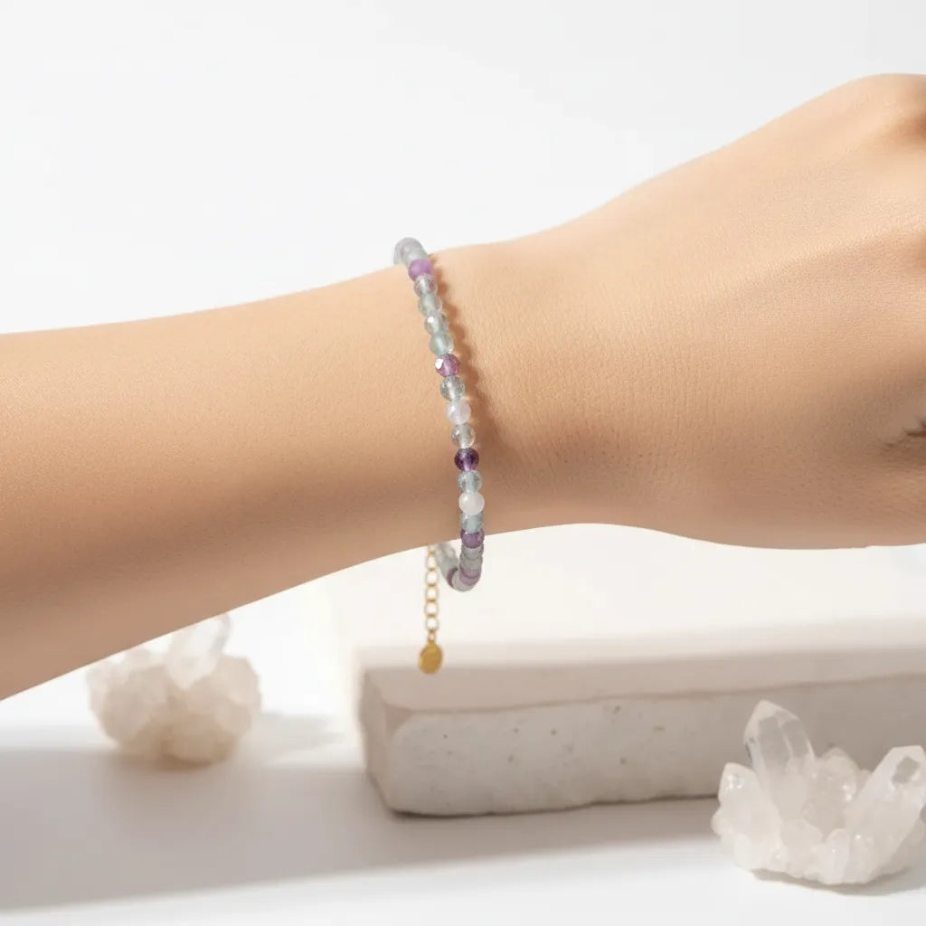 Woman wearing a fluorite gemstone beaded bracelet in gold, crown chakra jewelry