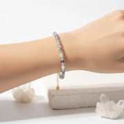 Woman wearing a fluorite gemstone beaded bracelet in gold, crown chakra jewelry