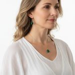 Woman wearing a green heart chakra necklace and earring set in gold