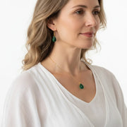 Woman wearing a green heart chakra necklace and earring set in gold