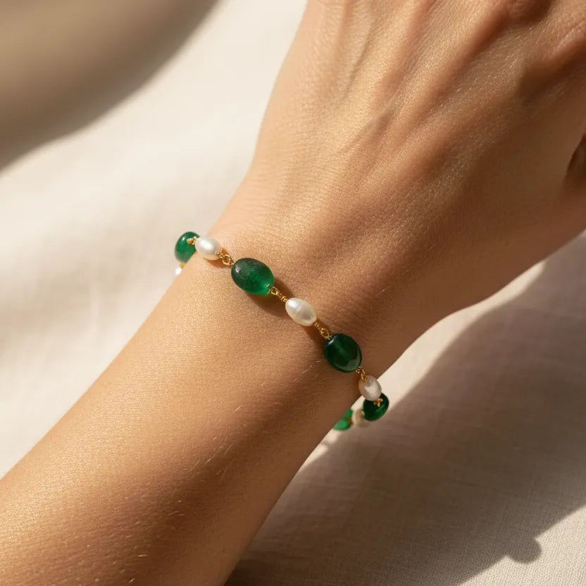Woman wearing emerald green and pearl beaded bracelet in gold