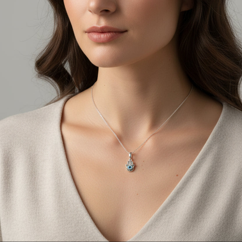 Sterling silver hamsa hand pendant with a blue evil eye centre worn as a necklace