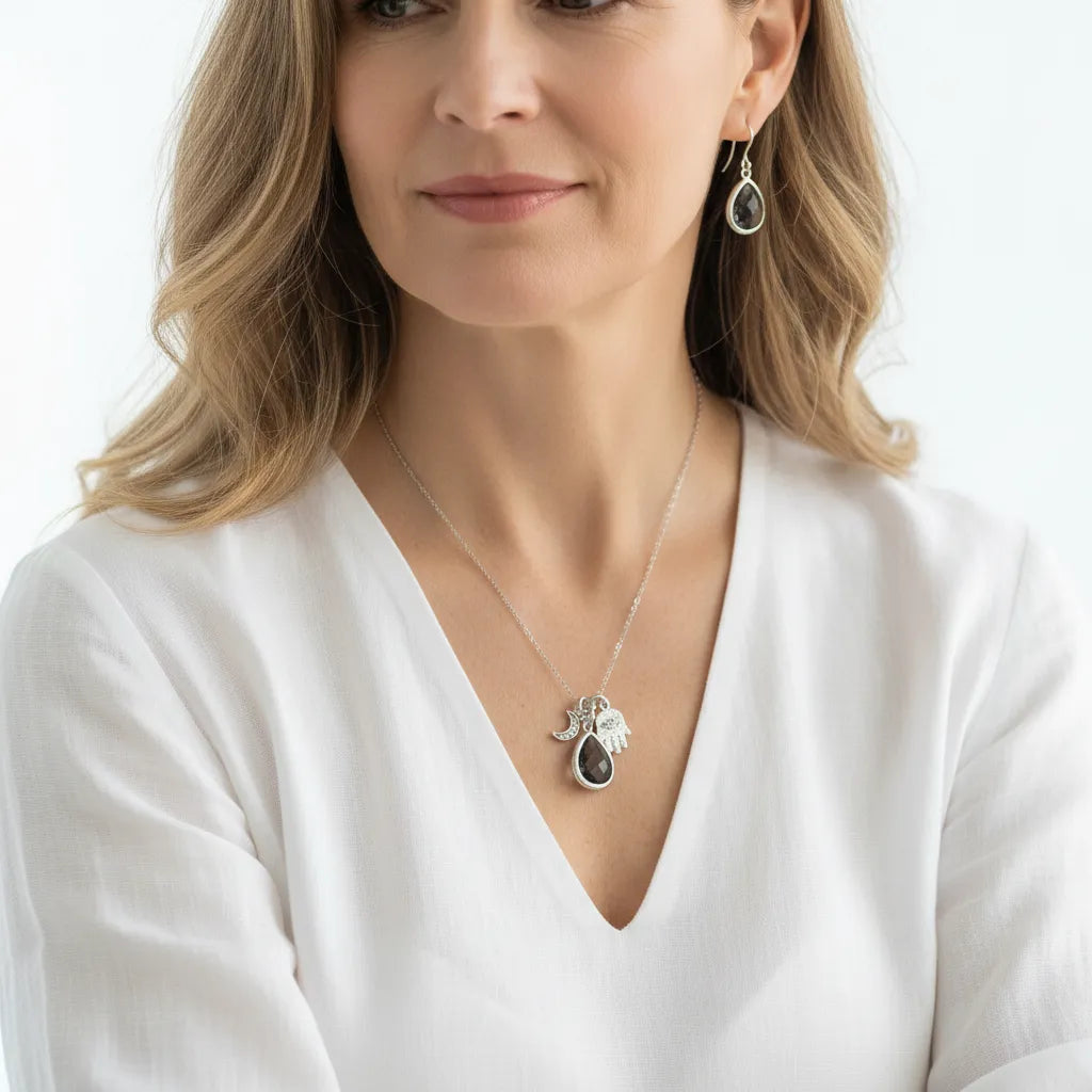 Hamsa hand and crescent moon necklace in dusk grey on a silver plated chain, worn at the collarbone