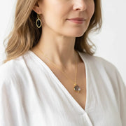 Woman wearing black marquis glass earrings with a gold rutilated quartz pear drop necklace