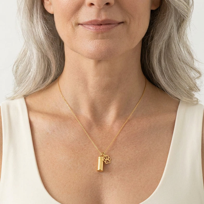 Woman wearing a gold paw print urn necklace, pet memorial jewelry