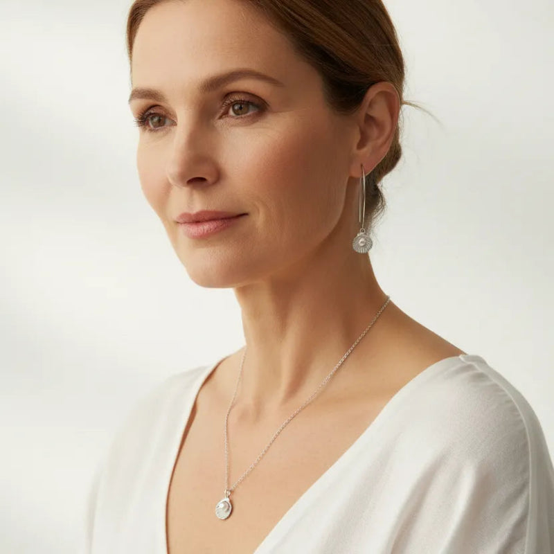 Woman wearing pearl in clam shell earrings and matching necklace in silver