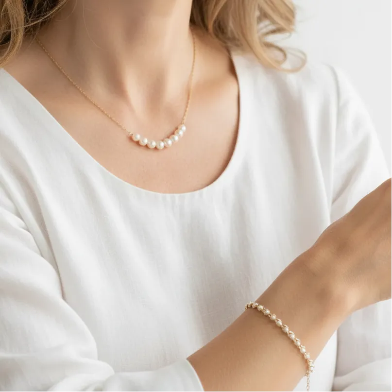 Woman wearing a pearl necklace with a matching pearl in chain bracelet, June birthstone jewelry