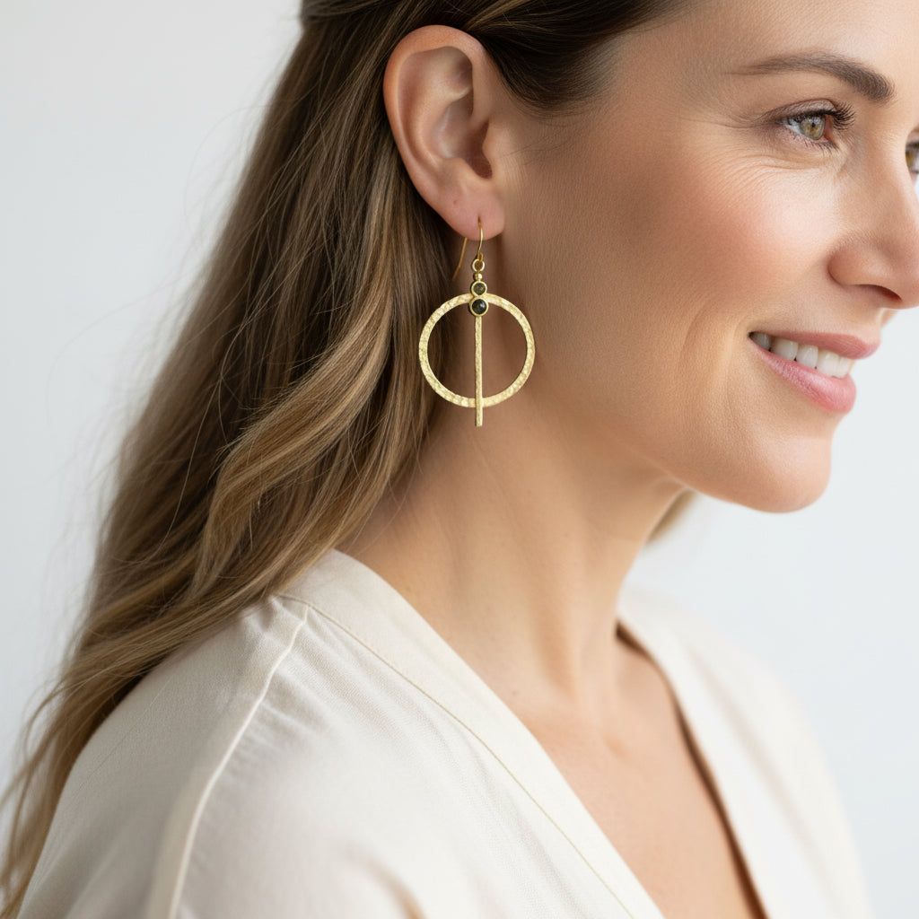 Woman wearing peridot hammered medallion drop earrings in gold — August birthstone jewelry