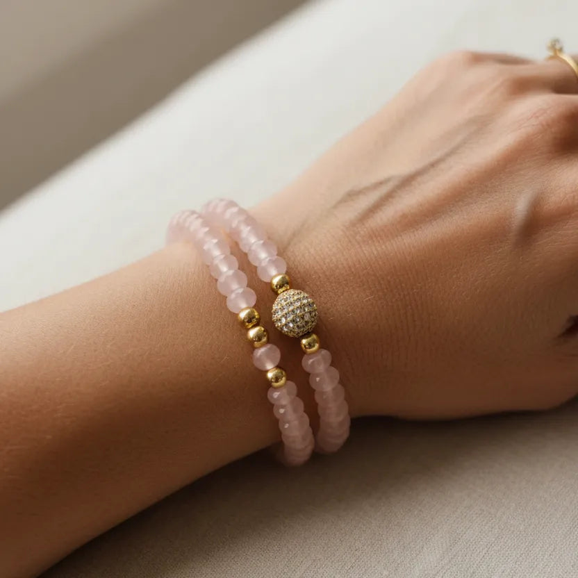 Woman wearing stacked pink gemstone bead bracelets in gold