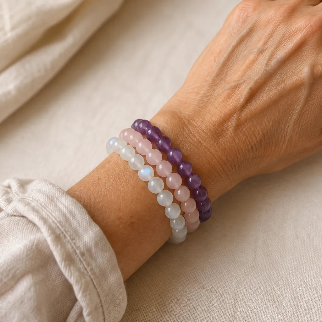 Woman wearing The Receiving Stack of moonstone, rose quartz and amethyst bracelets