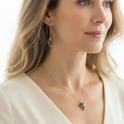 Woman wearing a black rutilated quartz shield necklace with matching earrings