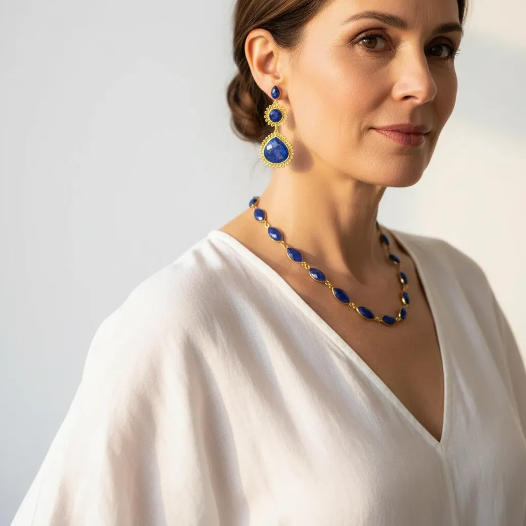 Woman wearing a genuine sapphire necklace with matching statement drop earrings, September birthstone jewelry