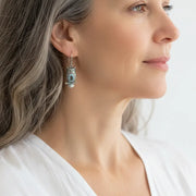 Woman wearing a silver owl drop earring set with a blue crystal, spirit animal jewelry