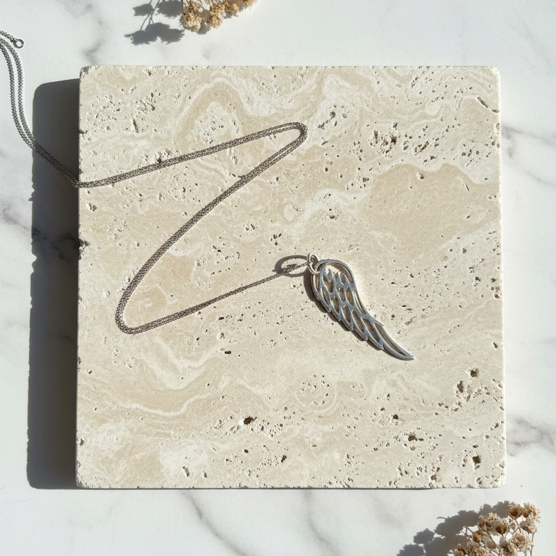 Angel wing pendant necklace in sterling silver worn at the collarbone