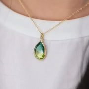 Woman wearing a gold tropical aura green quartz drop necklace — nature necklace for renewal
