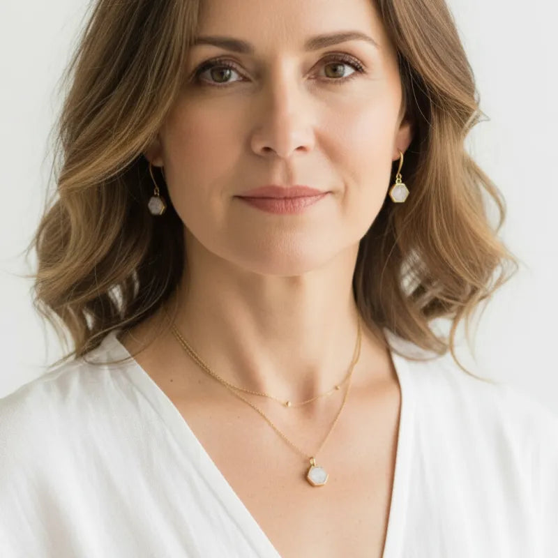 Woman wearing a white agate necklace and earring set on gold