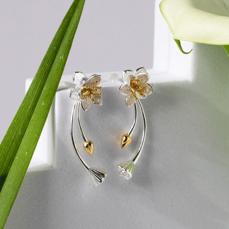Floral earrings with gold and silver details on a light gray background