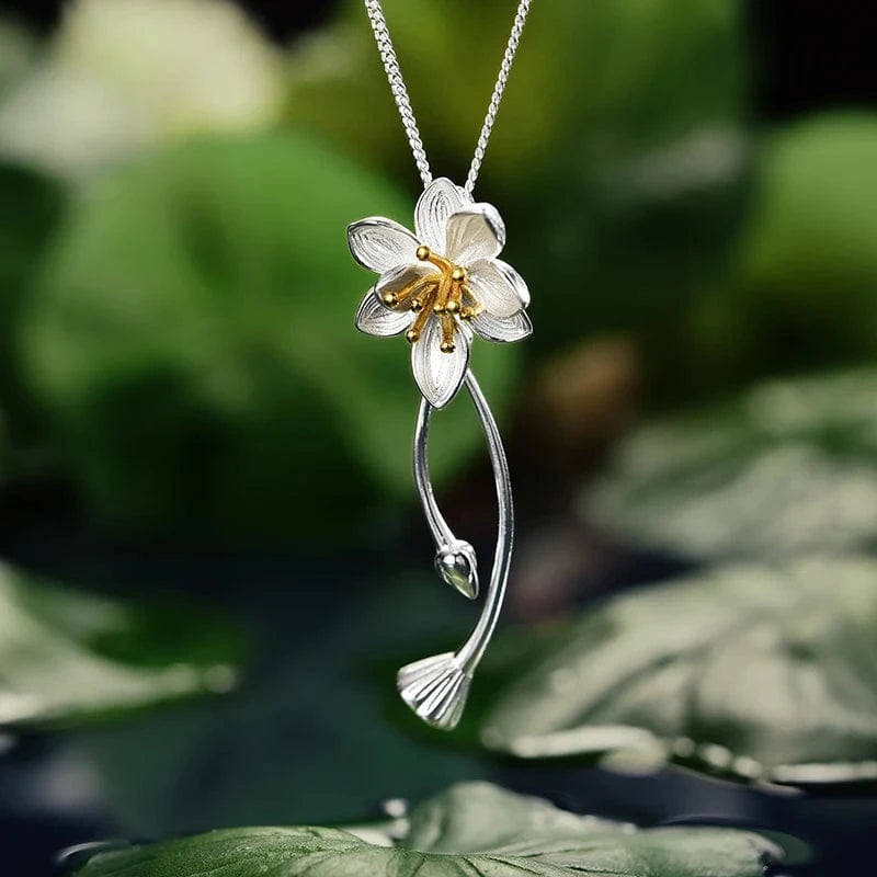 Floral silver necklace with a white flower pendant on a green leaf background