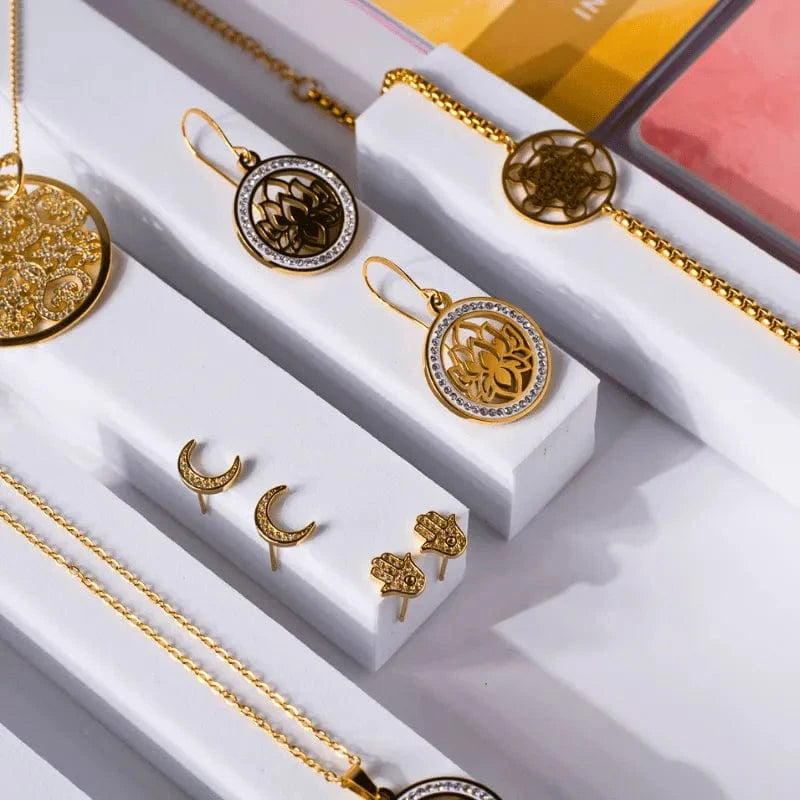Gold jewelry set including necklaces, pendants, and earrings on a white surface.