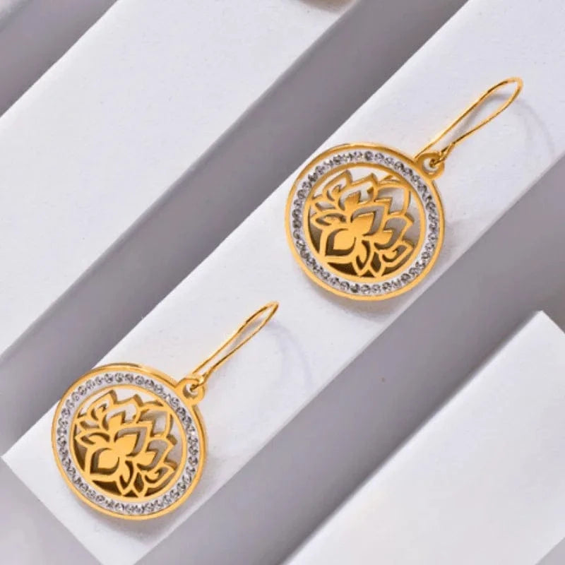Gold earrings with intricate designs on a white surface