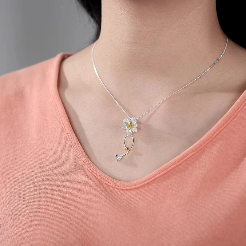 Necklace with a floral pendant worn by a person in a pink top.