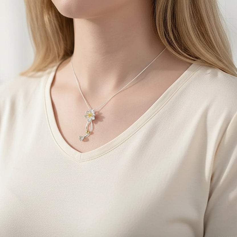 Necklace with a floral pendant worn by a person in a pink top.