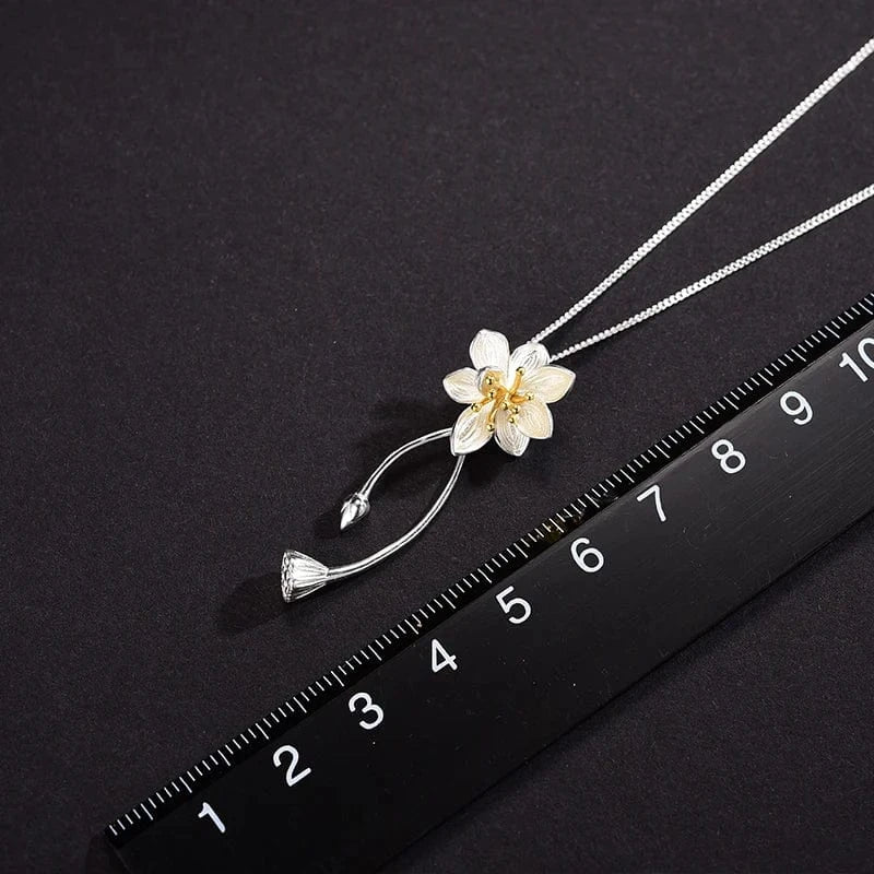Floral pendant necklace on a black background with a ruler for scale.
