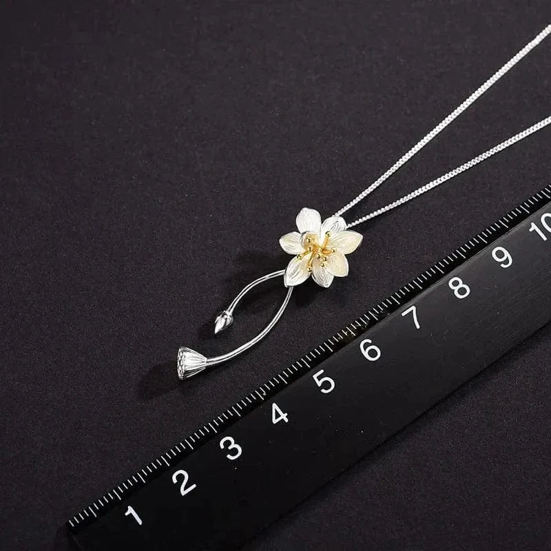 Floral pendant necklace on a black background with a ruler for scale.