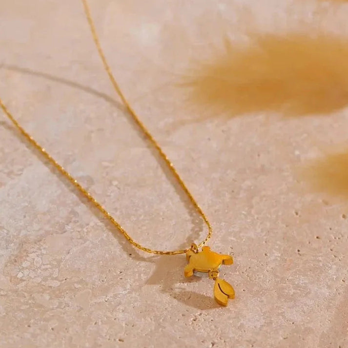 Gold necklace with a small pendant on a beige surface