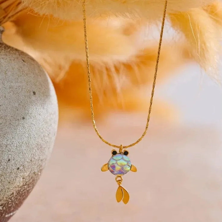 Gold necklace with a colorful pendant on a textured surface