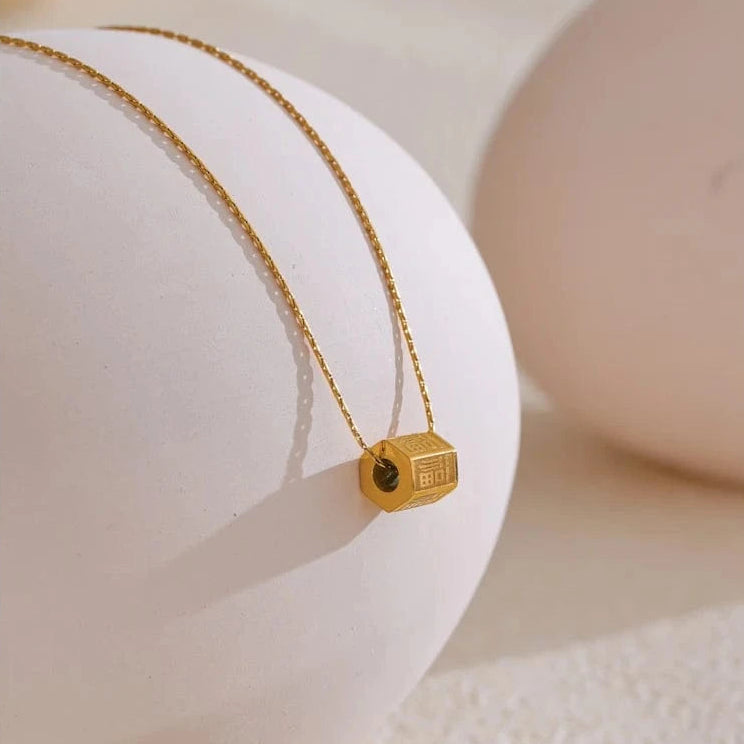 Gold necklace with a small pendant on a white surface